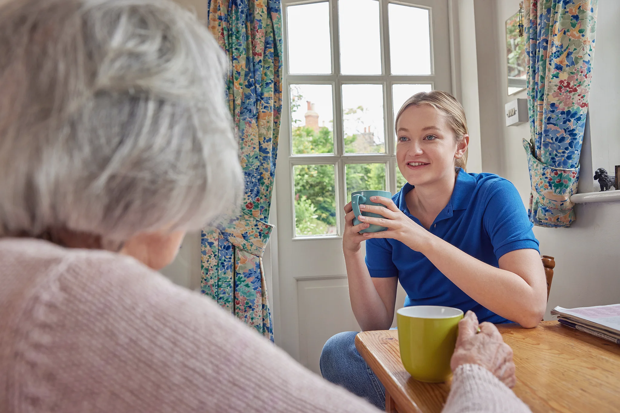 elderly-woman-and-care-giver-drinking-coffee-at-breakfast-table-together Caregiver with senior